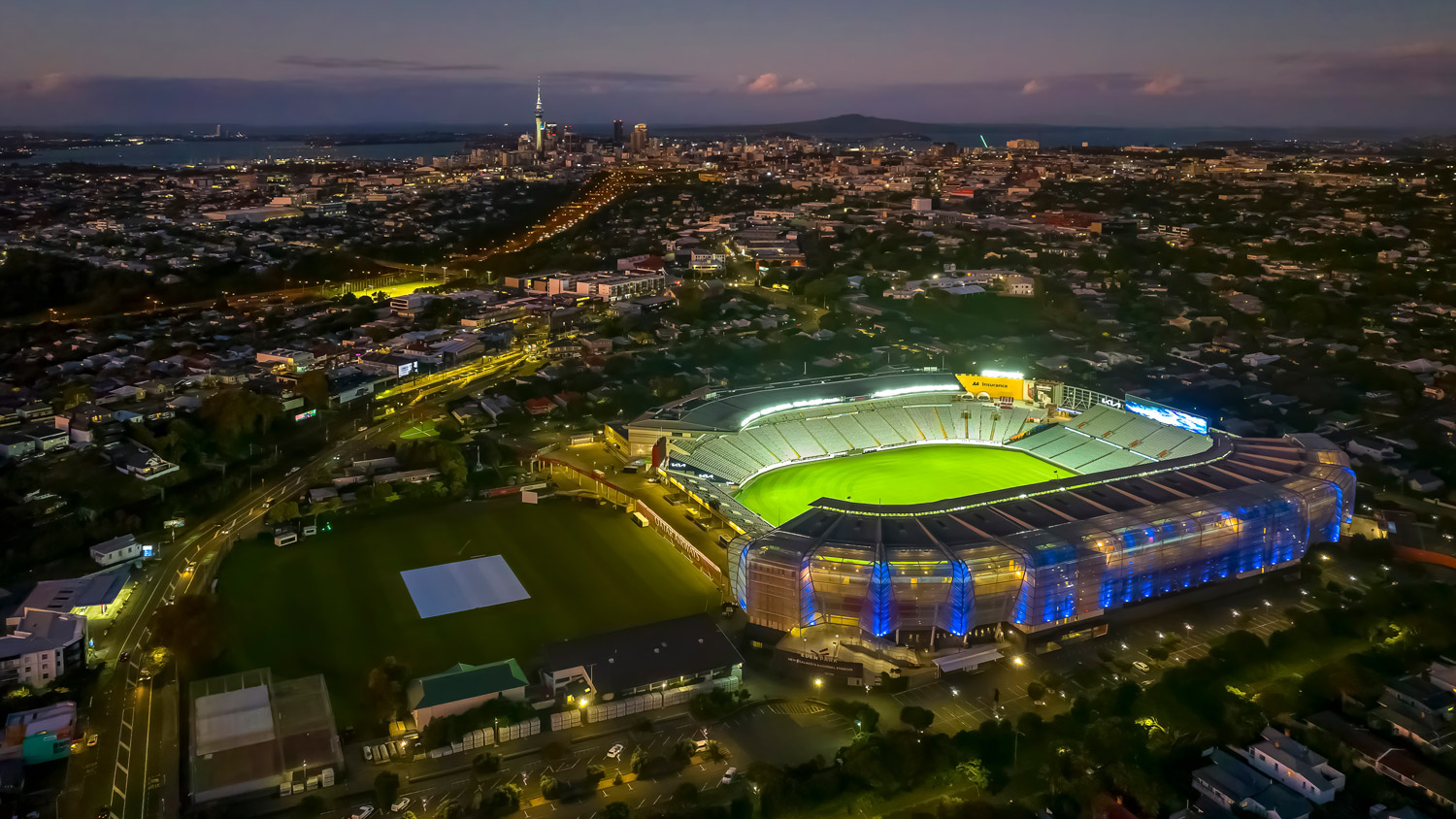 Eden Park stadium lit up at night with Auckland City in background