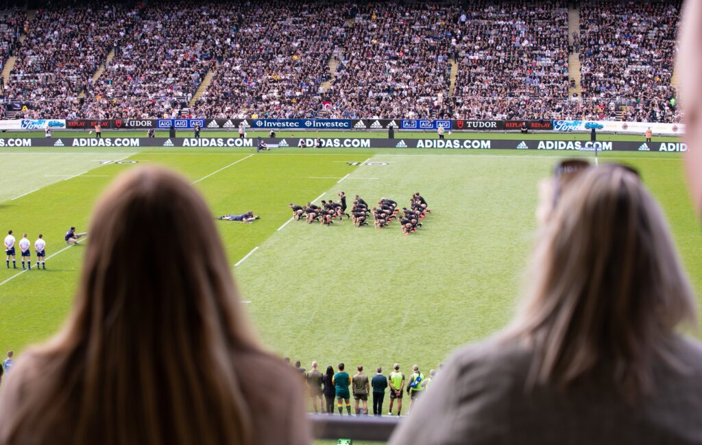 Photo of two people watching a rugby game from corporate suites